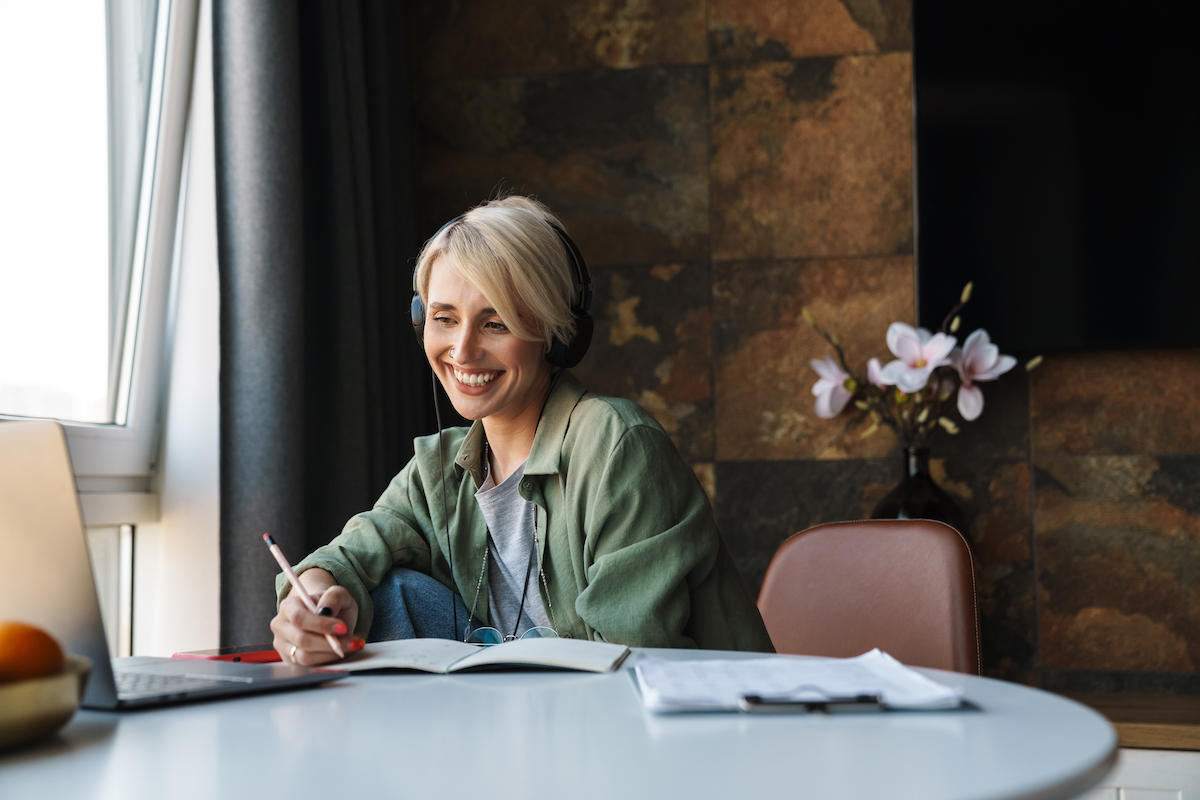 Nő nyugodt környezetben jegyzetel a One Brain vizsga felkészítő anyagához